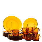 Amber glass dinnerware set including plates and cups on a white background
